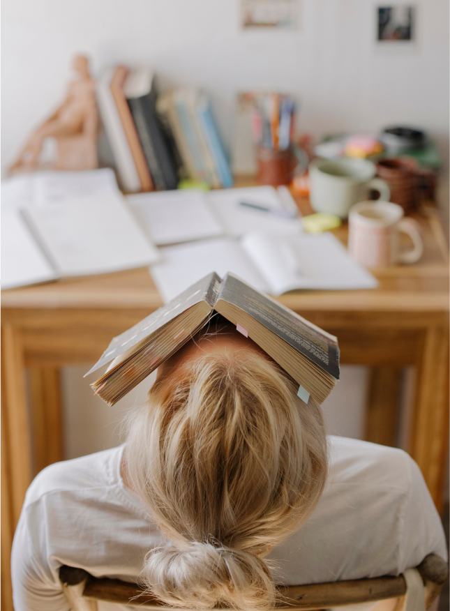 woman leaning back in chair with a book on her face