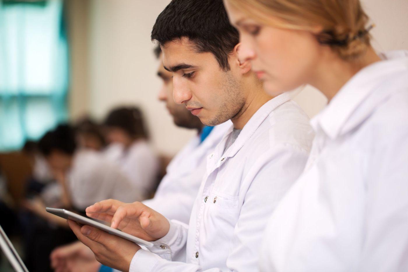 Medical students sitting in a classroom studying using digital devices.