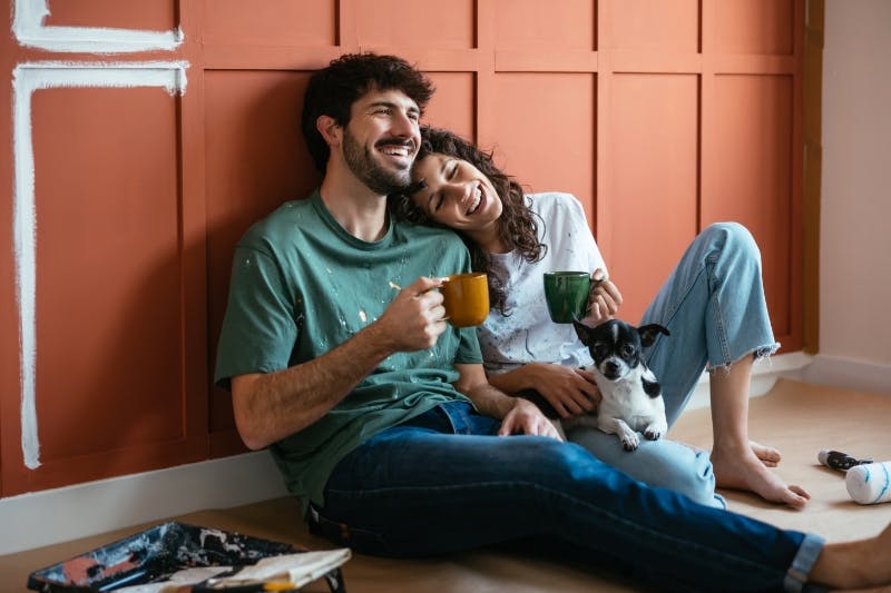 happy couple drinking coffee in front of new board and batten wall paid by personal loan