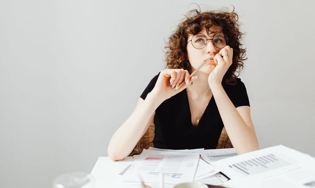 Woman sitting at a desk with papers thinking about getting a personal loan