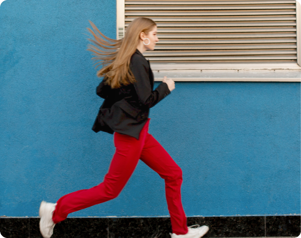 woman in red pants running along side walk